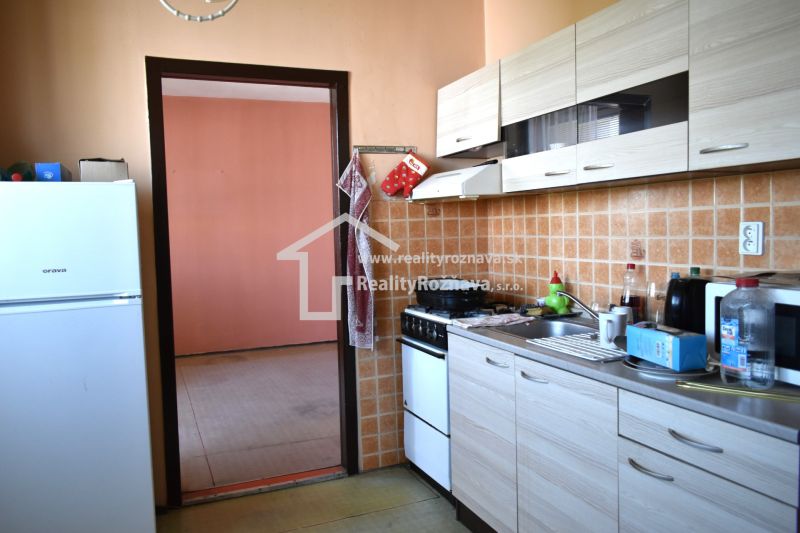 Küche in einer 3-Zimmer-Wohnung mit Fliesenverkleidung und Boden in Holzoptik.