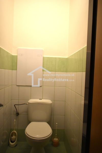 Badezimmer mit grün-weißen Fliesen und Toilette in einer 3-Zimmer-Wohnung.