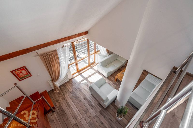 Wohnzimmer mit Holzboden, Treppe und großen Fenstern in einer Vierzimmerwohnung.