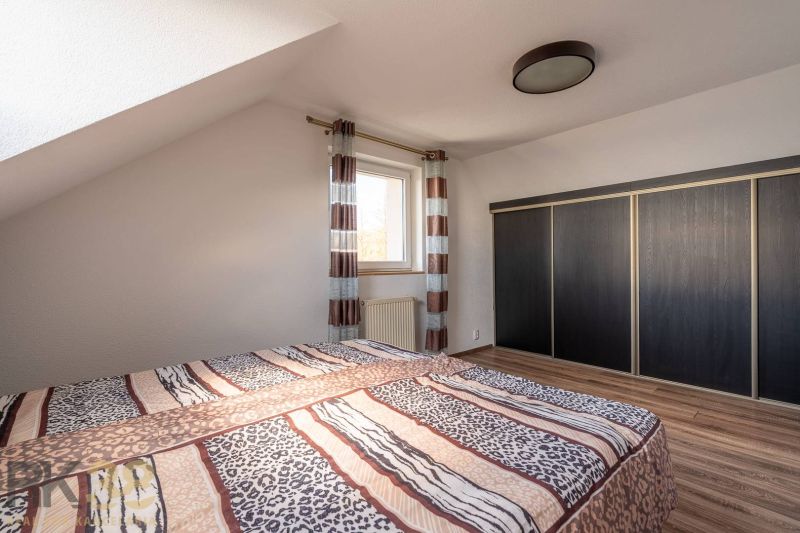 Schlafzimmer in einer 4-Zimmer-Wohnung mit Bett, großem Schrank und Boden in Holzoptik.