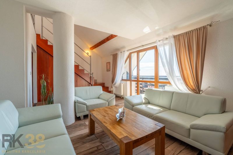 Wohnzimmer mit heller Couch, Treppe und Holzboden in einer 4-Zimmer-Wohnung.
