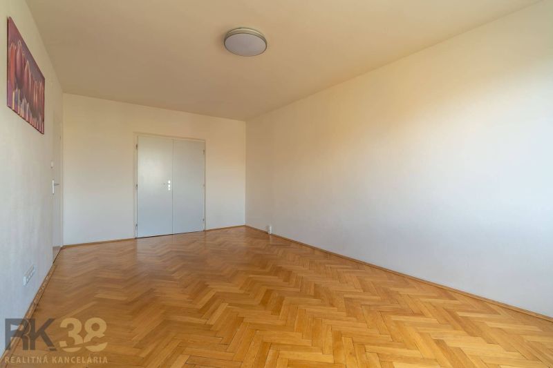 Ein Zimmer in einer 4-Zimmer-Wohnung mit weißen Wänden und einem Boden in Holzoptik.