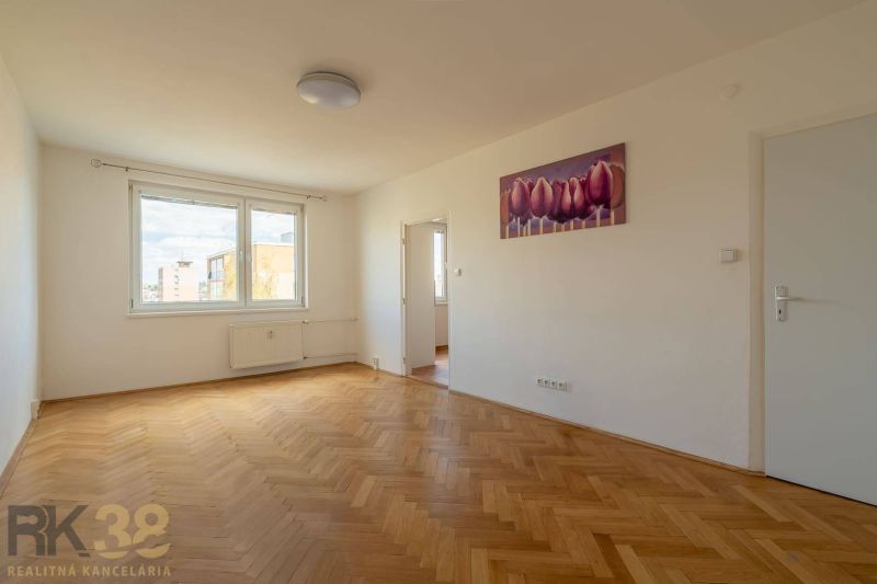 Ein geräumiges Zimmer mit einem großen Fenster, einem Boden in Holzoptik und einem Bild in einer 4-Zimmer-Wohnung.