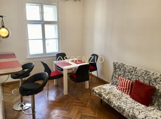 Wohnbereich in einer 2-Zimmer-Wohnung mit Holzboden und Esstisch.