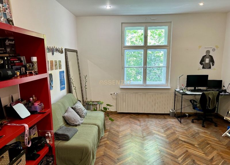Wohnzimmer in einer 2-Zimmer-Wohnung mit Holzboden, Sofa und Computertisch.