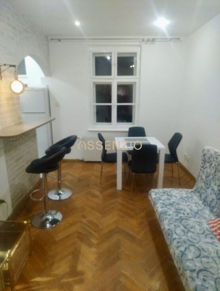 Wohnzimmer in einer 2-Zimmer-Wohnung mit Holzboden, Esstisch und Stühlen.
