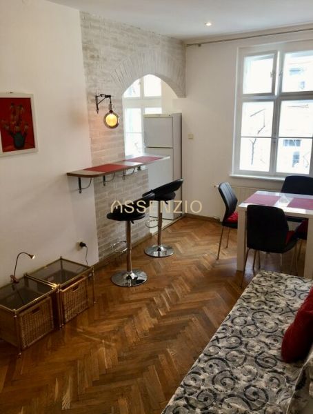 Wohnzimmer mit Barhockern, Esstisch und Holzboden.