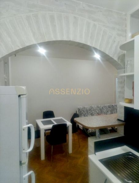 Küche in einer 2-Zimmer-Wohnung mit gewölbter Decke und Boden in Holzoptik.