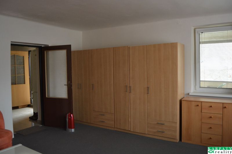 Izba v einem Einfamilienhaus mit braunen Schränken, einem Fenster und einer Tür.