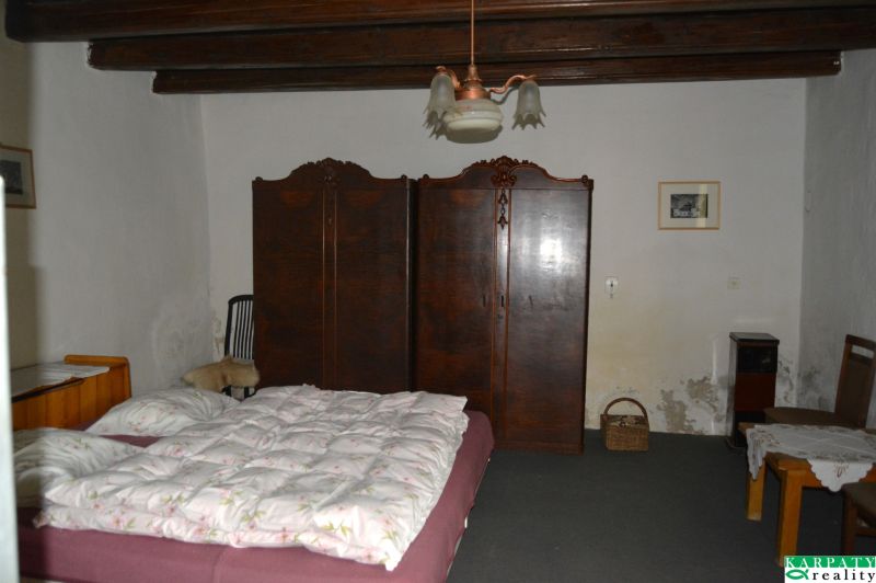 Schlafzimmer in einem Einfamilienhaus mit Bett, Schrank und Stühlen.