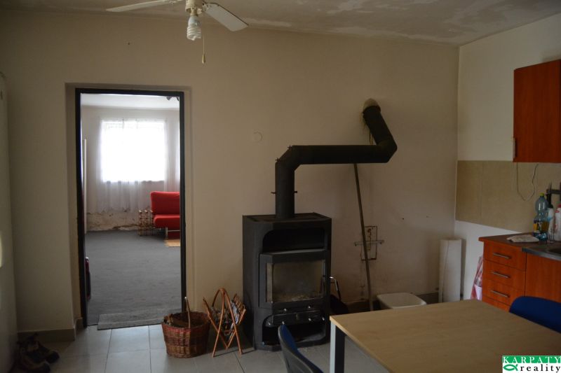 Innenraum eines Einfamilienhauses mit Kamin, Ventilator und rotem Sofa im Hintergrund.