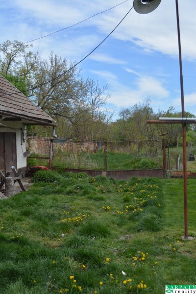 Ein Einfamilienhaus in Horné Saliby mit Rasen und Garten, umgeben von einem Zaun.