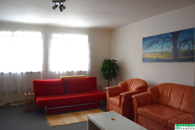 Wohnzimmer eines Einfamilienhauses mit rotem Sofa und orangefarbenen Sesseln.