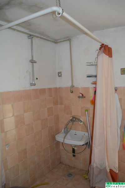 Badezimmer mit Fliesen und Vorhang in einem Einfamilienhaus, einfaches Waschbecken.
