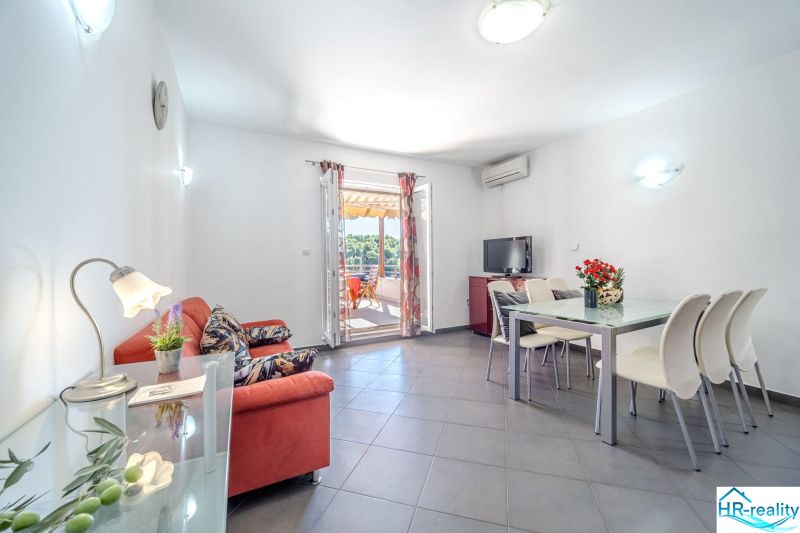 Helles Wohnzimmer mit Sofa, Esstisch und Terrasse in der Ferienwohnung.