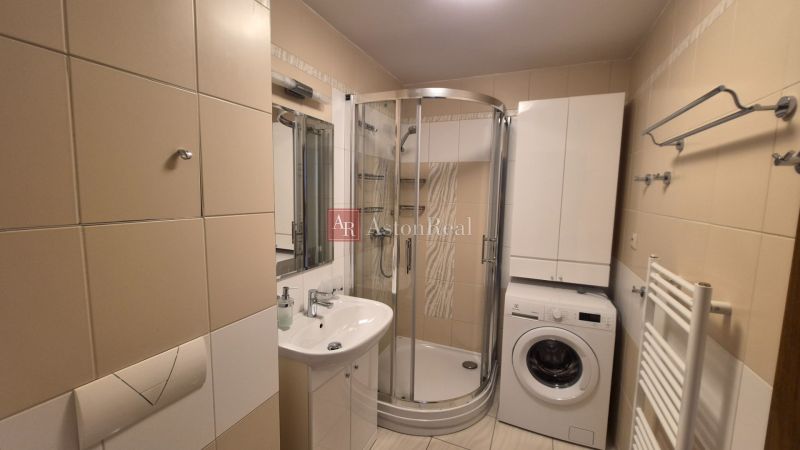Badezimmer mit Waschbecken, Duschkabine und Waschmaschine in einer Ferienwohnung.