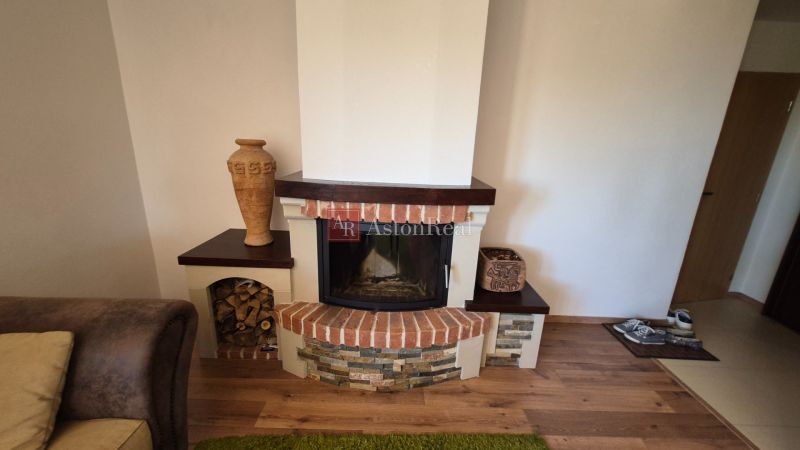 Kamin in einer Ferienwohnung mit dekorativem Stein und Boden in Holzoptik.