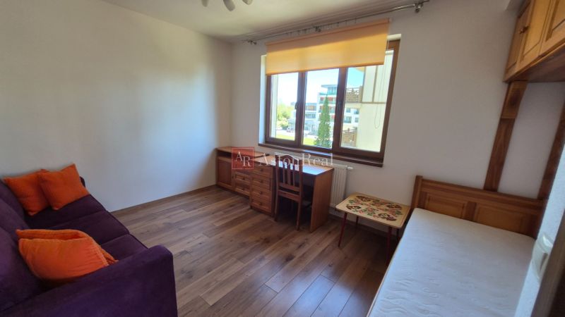 Ein Zimmer in einem Ferienapartment mit Sofa, Bett, Schreibtisch und Holzboden.