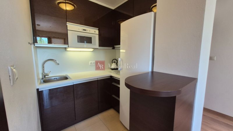 Kochnische in einer Ferienwohnung mit dunklen Schränken und weißen Geräten.