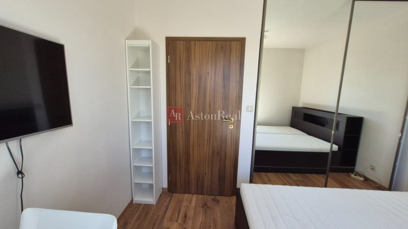 Ferienwohnung mit Bett, Kleiderschrank und Boden in Holzoptik.