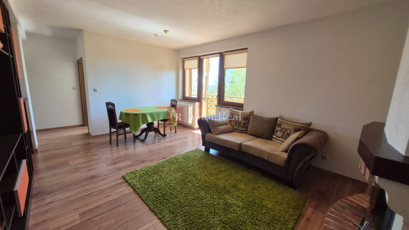 Wohnzimmer mit Sofa, Esstisch, Regal und Holzboden in einer Ferienwohnung.