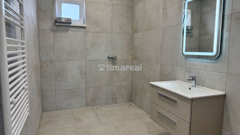 Badezimmer in einem Einfamilienhaus mit Fliesen, Spiegel und Dusche, barrierefreier Zugang.