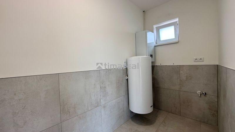 Ein Badezimmer in einem Einfamilienhaus mit Fliesen an den Wänden und einem Boiler.
