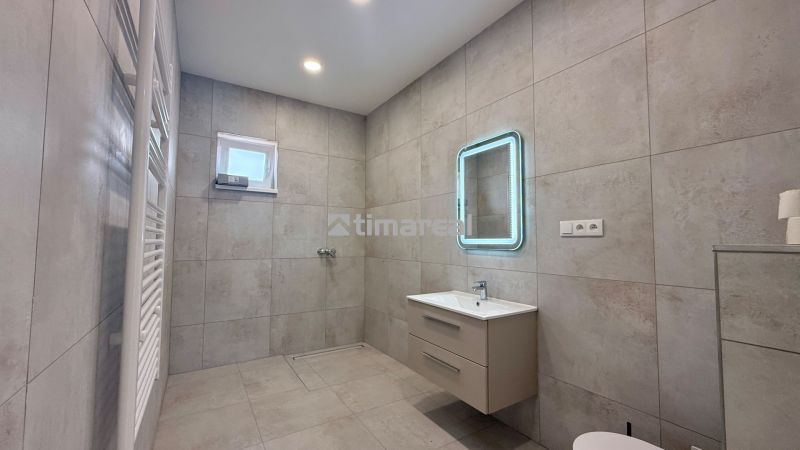 Badezimmer in einem Einfamilienhaus mit modernem Waschbecken, Spiegel und Handtuchheizkörper.