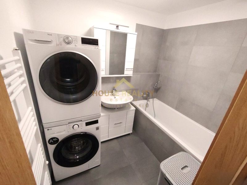 Badezimmer mit Badewanne, Waschmaschine und Trockner in einer 2-Zimmer-Wohnung.