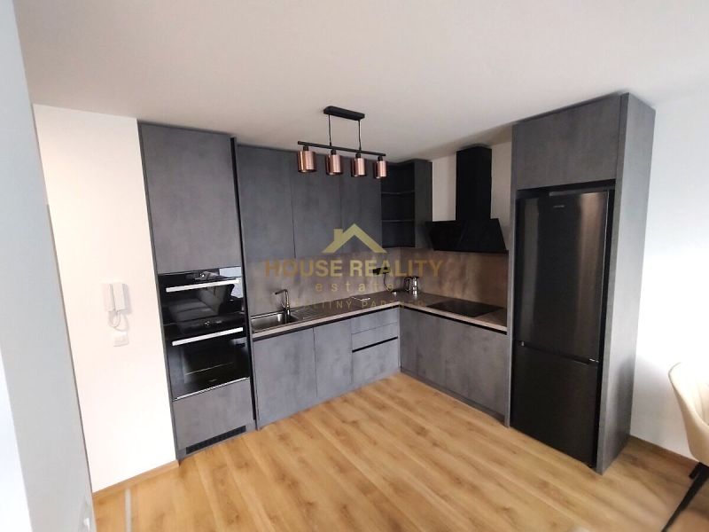 Küche mit dunkelgrauer Küchenzeile und Holzboden in einer Zweizimmerwohnung.
