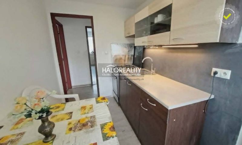 Eine Küche in einer 3-Zimmer-Wohnung mit Esstisch, Küchenzeile und einer Wand in Holzdekor.