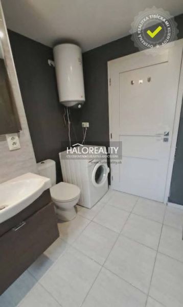 Badezimmer in einer 3-Zimmer-Wohnung mit Waschmaschine und Boiler, Fliesen in hellem Farbton.