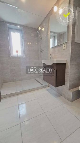 Badezimmer in einer 3-Zimmer-Wohnung mit Dusche und Waschbecken, Fliesen in hellen Farbtönen.