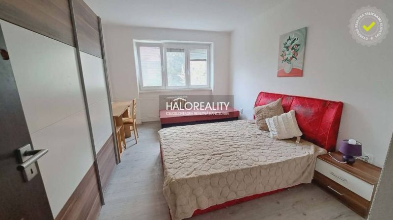 Schlafzimmer mit rotem Kopfteil und Holzboden in einer 3-Zimmer-Wohnung.