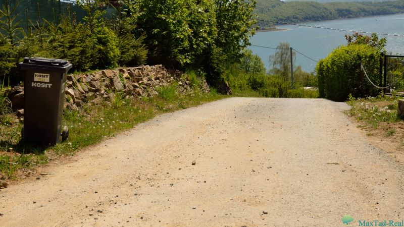 Befestigter Weg, Mülleimer und Blick auf den See in Neue Kelča, Erholungsgrundstücke.