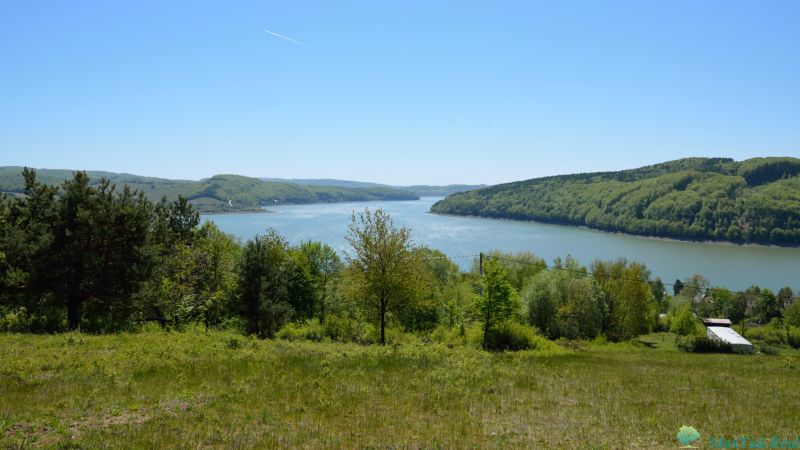 Blick von den Erholungsgrundstücken in Nová Kelča auf den von Wäldern umgebenen See.