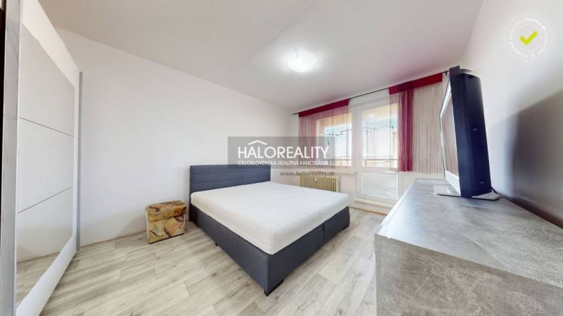 Schlafzimmer mit Bett, Fernseher und Holzboden in einer Zweizimmerwohnung.