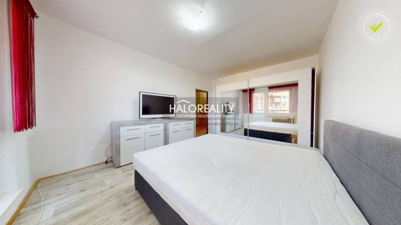 Schlafzimmer mit weißem Interieur und Holzboden in einer 2-Zimmer-Wohnung.