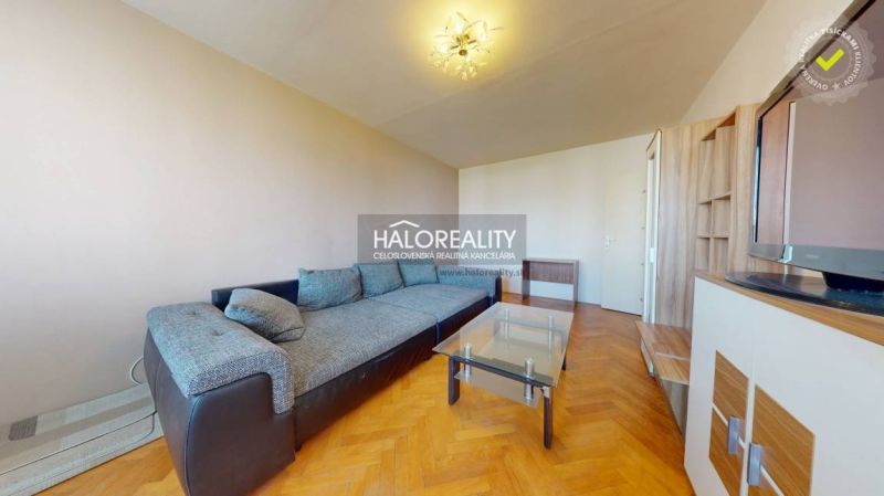 Wohnzimmer in einer 2-Zimmer-Wohnung mit einem Sofa und einem Boden in Holzoptik.
