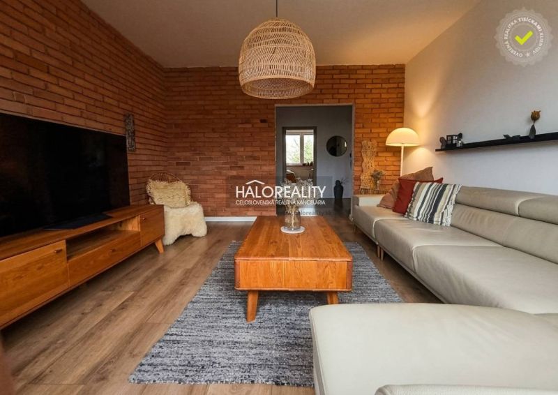 Wohnzimmer in einer 3-Zimmer-Wohnung mit Ziegelwand und Boden in Holzoptik.
