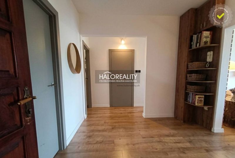 Flur in einer 3-Zimmer-Wohnung mit Holzboden und eingebautem Regal.