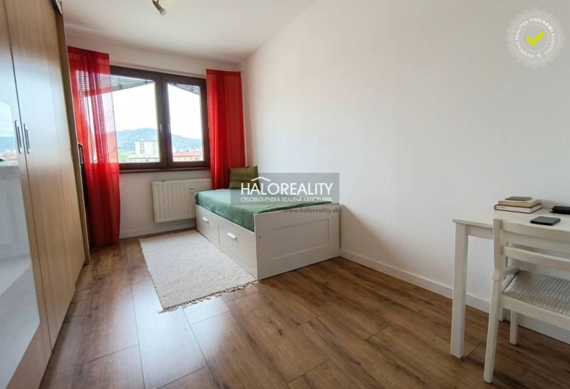 Ein helles Zimmer mit einem Bett, einem Tisch und einem Holzboden in einer 3-Zimmer-Wohnung.