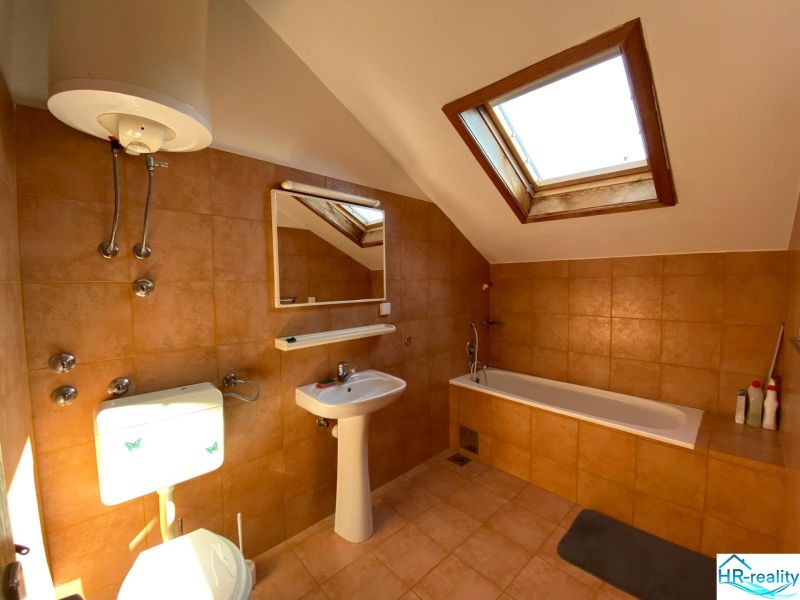 Badezimmer in einer Ferienwohnung mit Badewanne und Dachfenster.