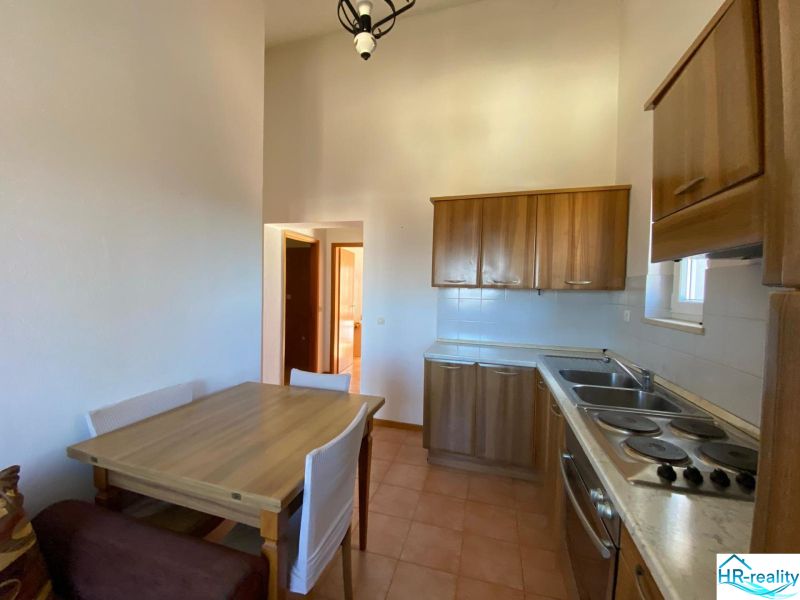 Küche in einer Ferienwohnung mit Holzschränken und Esstisch.