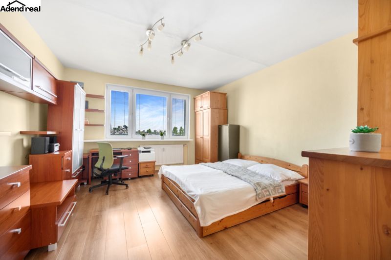 Schlafzimmer in einer 3-Zimmer-Wohnung mit Bett, Schreibtisch und Boden in Holzoptik.