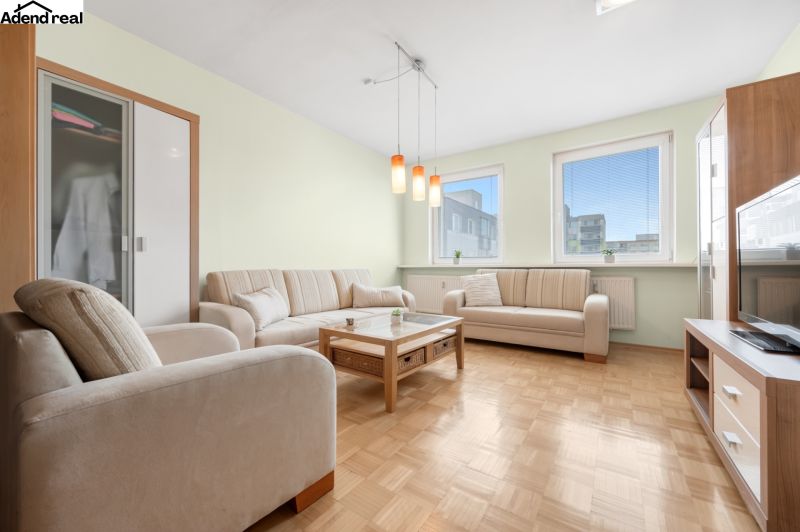 Wohnzimmer in einer 3-Zimmer-Wohnung mit einer Eckcouch und einem Boden in Holzoptik.