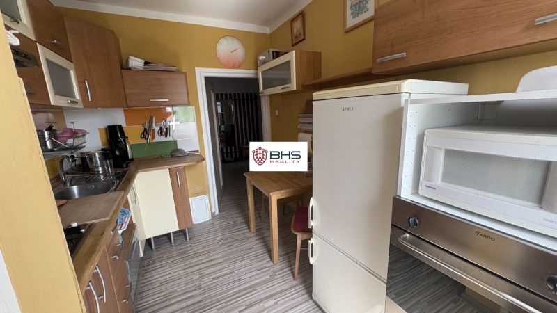 Küche in einer 2-Zimmer-Wohnung mit gelben Wänden und einem Boden in Holzoptik.
