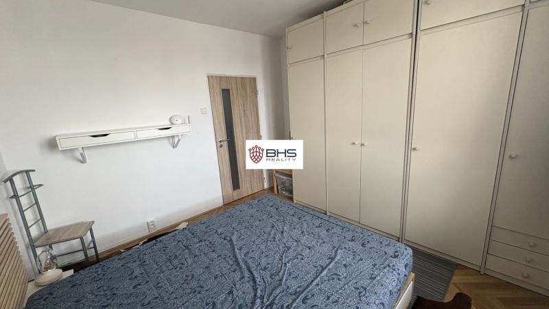 Schlafzimmer mit großem Kleiderschrank und Holzboden in einer 2-Zimmer-Wohnung.