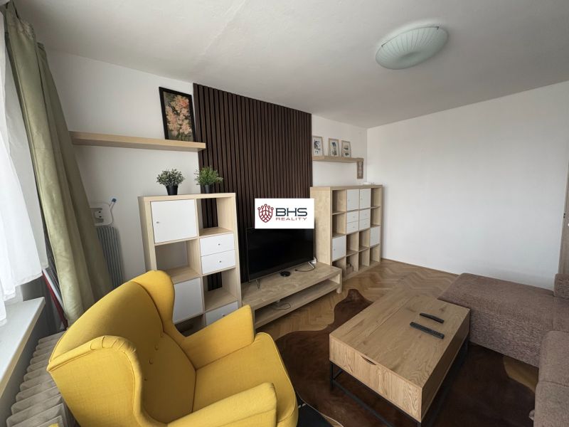 Wohnzimmer in einer 2-Zimmer-Wohnung mit Holzboden und gelbem Sessel.