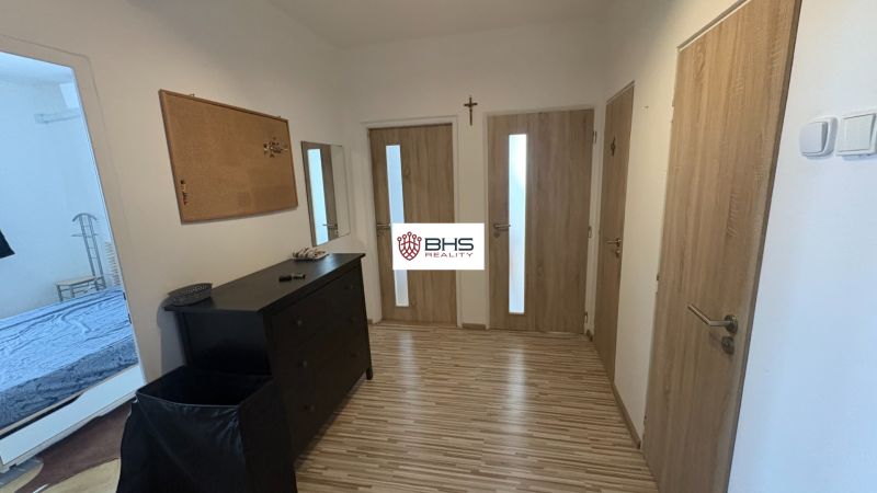 Ein Flur mit Holztüren und einer Kommode in einer 2-Zimmer-Wohnung, Boden mit Holzdekor.